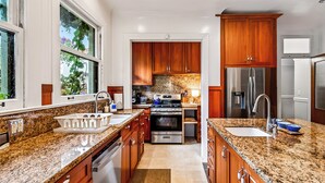Eine moderne Küche mit Granitarbeitsplatten, Edelstahlgeräten, Holzausbau und einem großen Fenster.