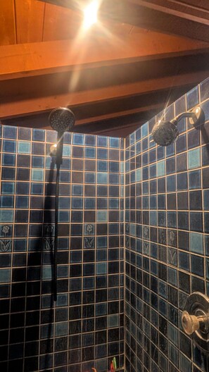 Eine Dusche mit blauen Fliesen an den Wänden und einer Holzboden.