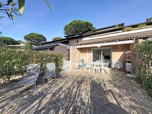 Eine Villa mit Terrasse, Sitzgelegenheiten im Freien und Blick auf den umliegenden Garten.