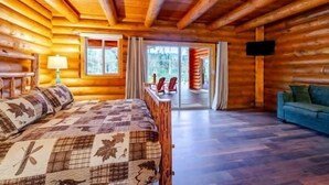 A log cabin interior with a bed, a sofa, and a TV.