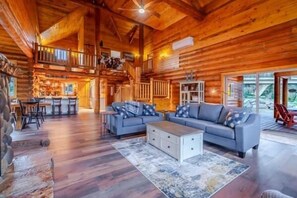 A spacious log cabin interior with a large living area, a kitchen, and a dining area.