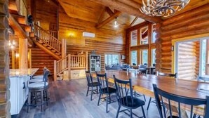 A log cabin interior with a dining area, bar, and staircase. - Tranquil River Front log cabin retreat (Gates)