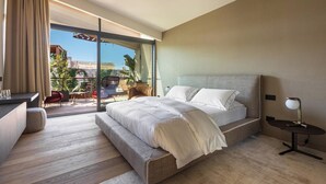 A modern hotel room with a large bed, a desk, and a balcony with outdoor seating. - MBH | Panoramic Room (Diso Spongano)