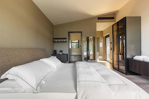 A hotel room with a large bed, a desk, a mirror, and a wardrobe.
