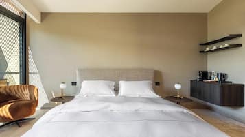 Ein modernes Hotelzimmer mit einem großen Bett, zwei Nachttischen, einem Sessel und einem Kleiderschrank, mit Blick durch ein Fenster.