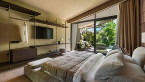 A modern bedroom with a large bed, a TV mounted on a wall, and a sliding glass door leading to a patio with outdoor furniture.