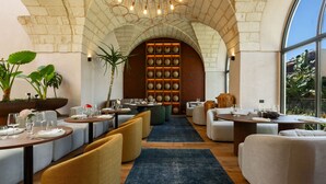 A restaurant with a brick archway, tables set with plates and glasses, and a display of vases.