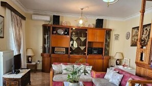 Un soggiorno con divano, tavolino, televisore e un mobile contenitore con ripiani.