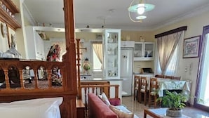 Una camera da letto con un letto a baldacchino, un angolo salotto con divano e poltrone, un settimino in legno, e vista sulla cucina e sala da pranzo.
