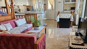 Un soggiorno con un divano, un tavolo da pranzo e una cucina sullo sfondo.
