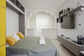 A modern hotel room with a bed, a TV, a desk, and a wardrobe. - Elegant Luxury Apartment on Navigli -Wi-Fi Fast, Metro, Duomo, Air Conditioning (Milano)