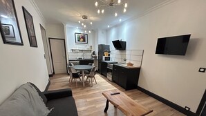Uma sala de estar moderna com um sofá, uma mesa de centro de madeira e um espaço de refeições com cadeiras e uma mesa.