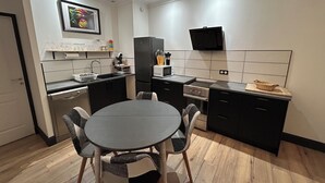 Uma cozinha moderna com mesa de jantar, cadeiras, geladeira, micro-ondas e pia.