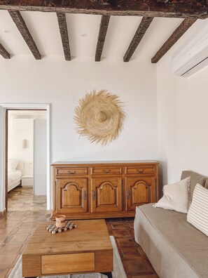 Un soggiorno con un armadietto in legno, una decorazione murale in vimini e un sottobicchiere a scacchi su un tavolo di legno.