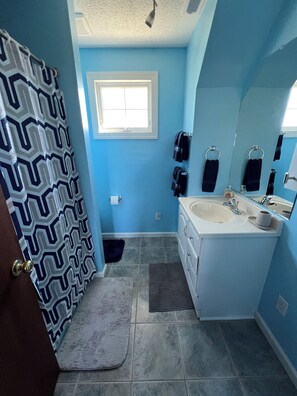 A bathroom with blue walls, a white sink, a mirror, and a shower curtain.