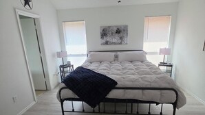Un dormitori amb un llit, un ventilador de sostre, una decoració amb estrelles, un quadre i dues làmpades de nit.