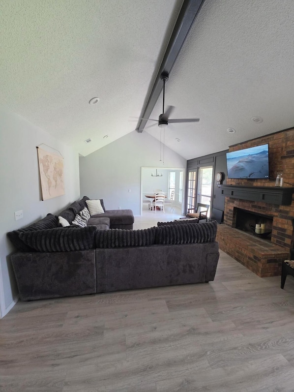 A modern living room with a sectional sofa, a fireplace, and a television mounted on the wall.