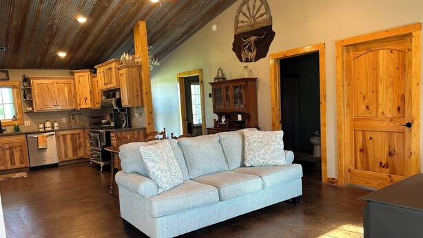 A rustic kitchen with wooden cabinets, a dining area with a light blue sofa, and a ceiling fan.