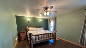 A bedroom with a wooden bed, a ceiling fan, and a nightstand.