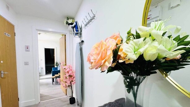 Ein Flur mit einem Spiegel, einem Blumenstrauß und einer Tür mit der Aufschrift 'TOILET'.