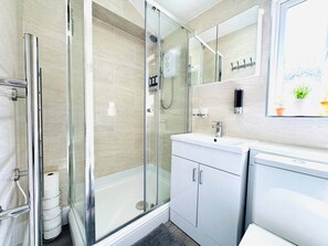 A modern bathroom with a glass-enclosed shower, a white sink, and a mirror above the sink. - Stylish 2-Bed Flat in Cardiff (Cardiff)
