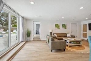 Ein modernes Wohnzimmer mit einer Couch, einem Couchtisch und großen Fenstern.