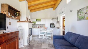 Ein gemütliches Wohnzimmer mit Holzbalkendecke, einem blauen Sofa, einer Holzkommode und einem Fernseher.