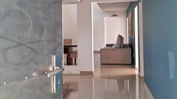 A modern interior with a reflective floor, a blue accent wall, and a neutral-toned sofa. - Prainha, Rio de Janeiro (Rio de Janeiro)