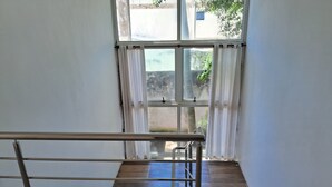 A staircase with metal railings, wooden steps, and a view through a window with curtains. - Prainha, Rio de Janeiro (Rio de Janeiro)