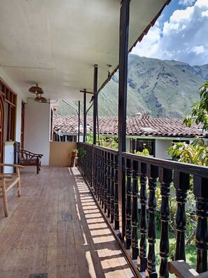 Un balcon en bois avec une rambarde en métal, un banc et une vue sur une montagne.