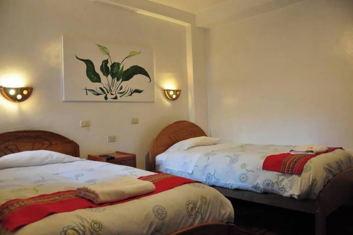 Una camera d'albergo con due letti, un'opera d'arte appesa al muro e due applique.