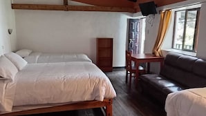 Una habitación con una cama, un sofá, una mesita y un ventanal con cortinas.