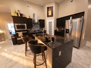 Una cocina moderna con una isla central, electrodomésticos de acero inoxidable y armarios oscuros.