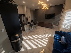 Una cocina moderna con comedor, un sofá y un televisor montado en la pared.