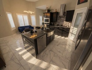 A modern kitchen with a central island, built-in appliances, and a dining area with a blue sofa.