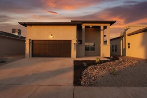 A modern two-story house with a garage, a covered entryway, and a landscaped front yard.