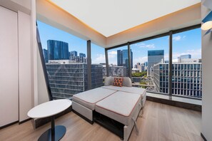 A modern bedroom with a city view, a sofa, a small table, and a large window. - Holiday Inn Express Shenzhen Bay By Ihg (Shenzhen)