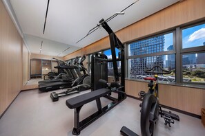 A gym with exercise equipment, a bench, and large windows with a city view. - Holiday Inn Express Shenzhen Bay By Ihg (Shenzhen)