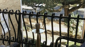 A balcony with wicker furniture, a small table, and a hanging wind chime. - Cozy Vintage Studio Close To Downtown (Mobile)