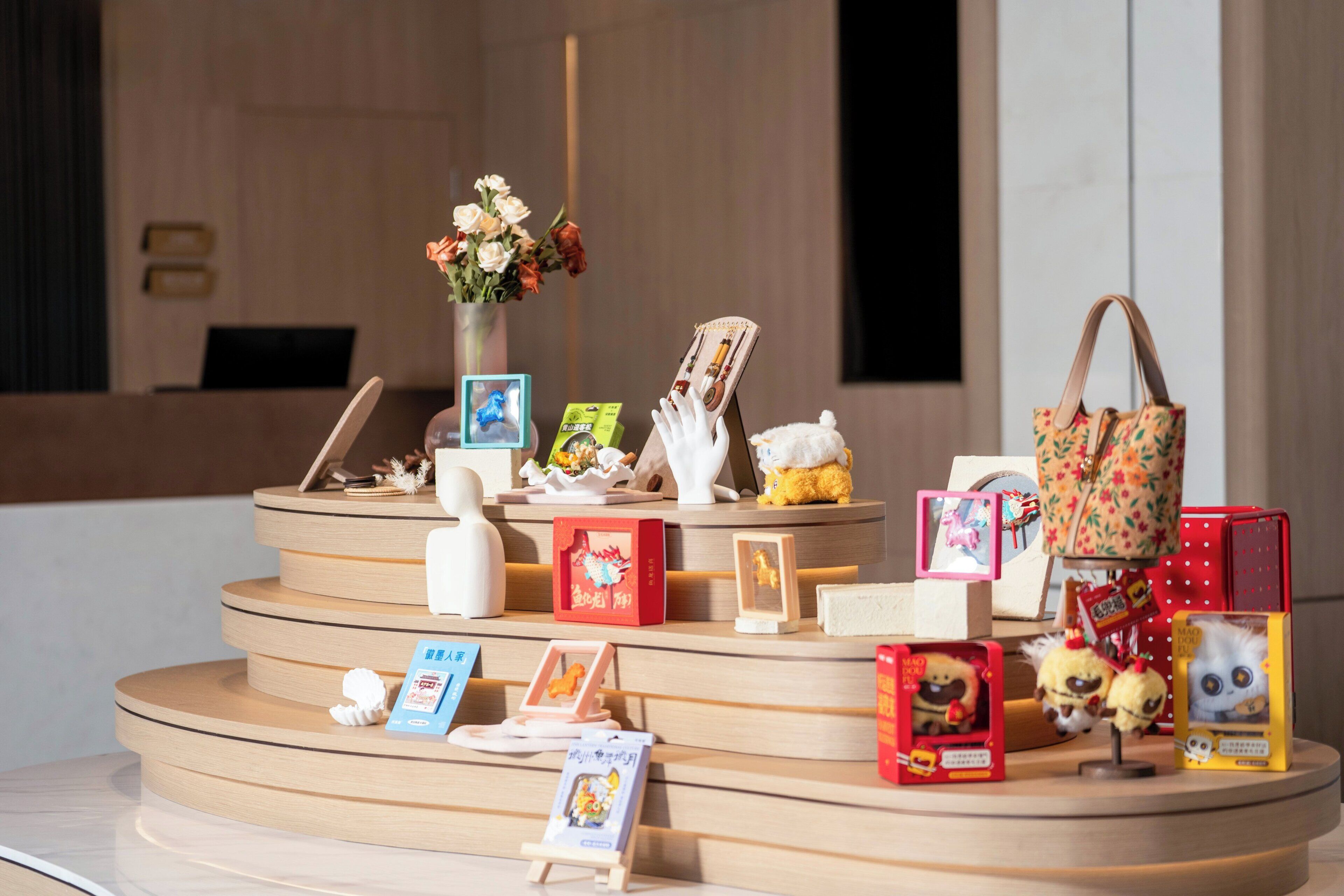 Una exhibición con diversos objetos, incluyendo un jarrón con flores, un peluche, un bolso de mano y varias fotografías enmarcadas.