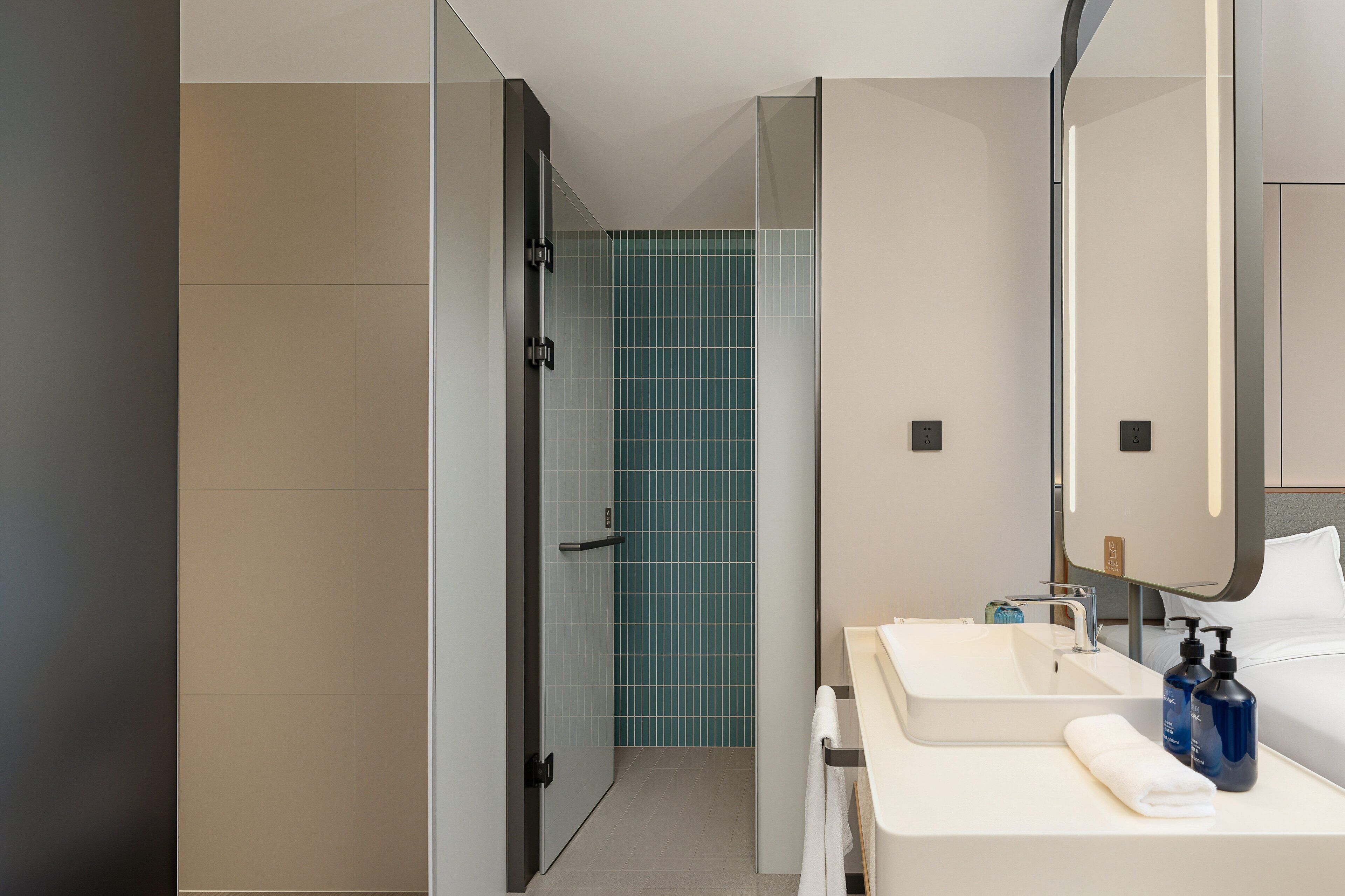 A modern bathroom with a shower, two sinks, and a large mirror.