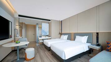 A modern hotel room with a large bed, a desk, a chair, and a television.