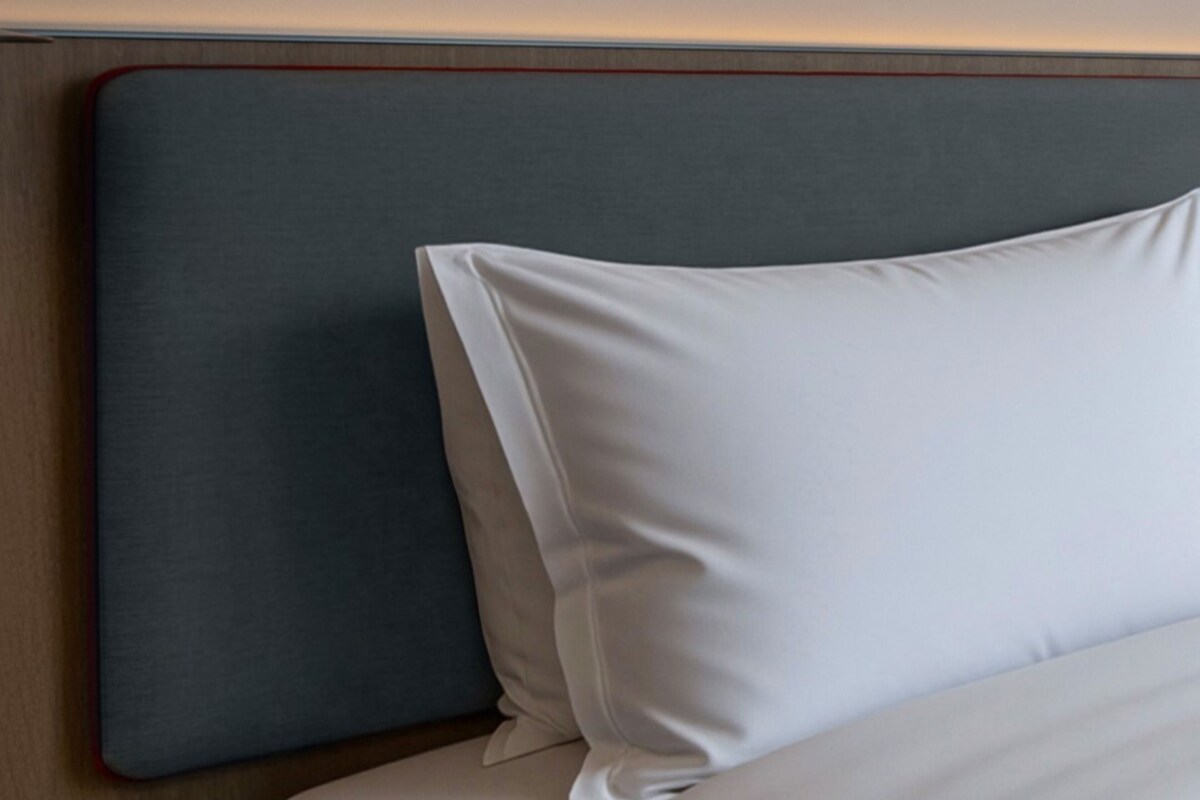 A bed with a grey headboard and white pillows.