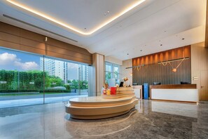 A modern hotel reception area with a curved reception desk, large windows offering a view of the cityscape, and a clean, minimalist interior design. - Holiday Inn Express Huangshan Tunxi High-Tech Zone By Ihg (Huangshan)
