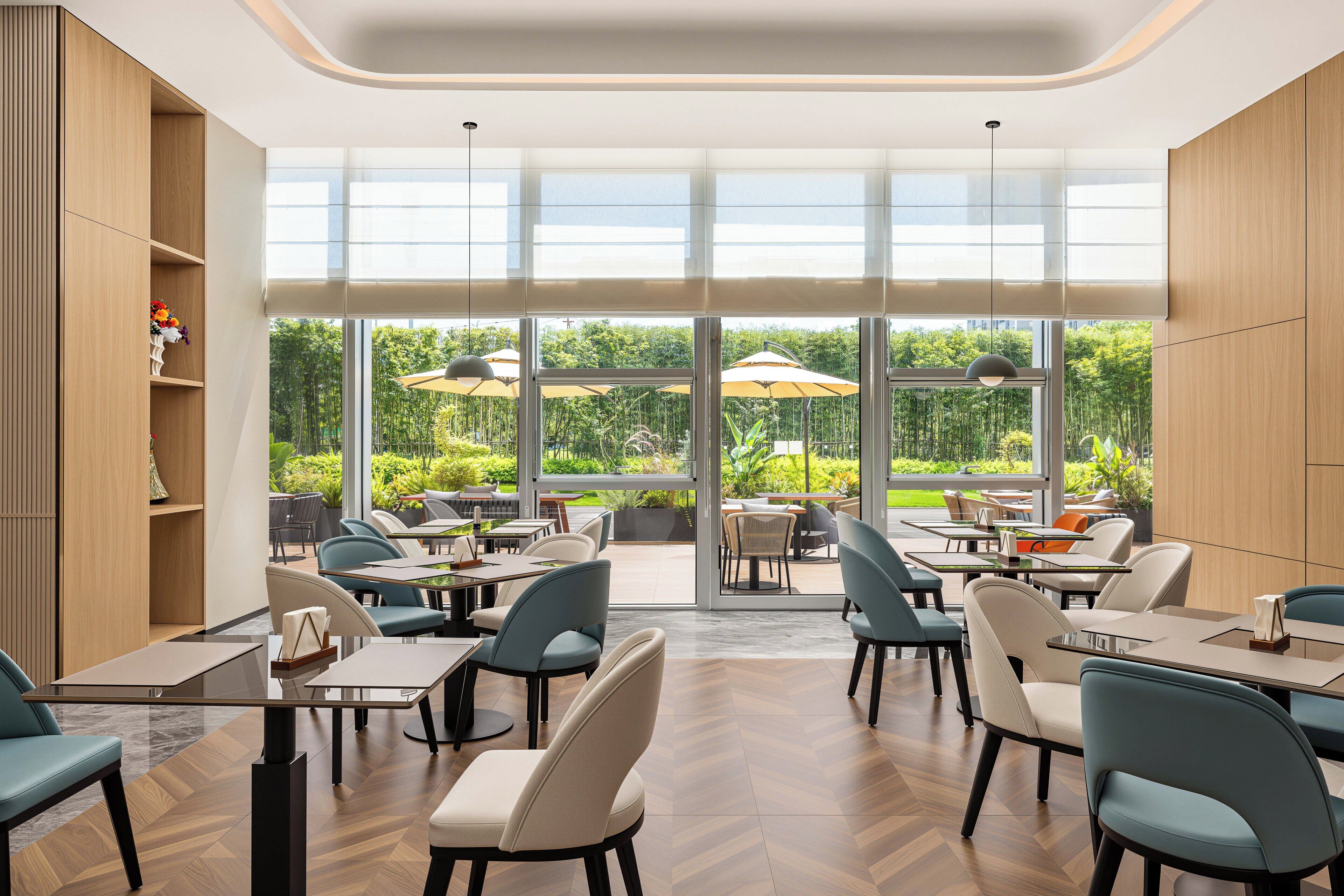 A modern dining area with large windows, wooden paneling, and a variety of seating options.