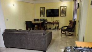 Un salon avec un canapé, une table à manger et des chaises, un téléviseur et une cuisinière à gaz.