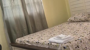 Une chambre à coucher avec un lit, des rideaux, une table de chevet et une tête de lit.