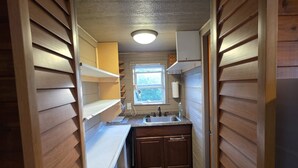Un couloir étroit aux murs en bois, avec une fenêtre, un lavabo et une pancarte sur laquelle on peut lire « LAKE ».