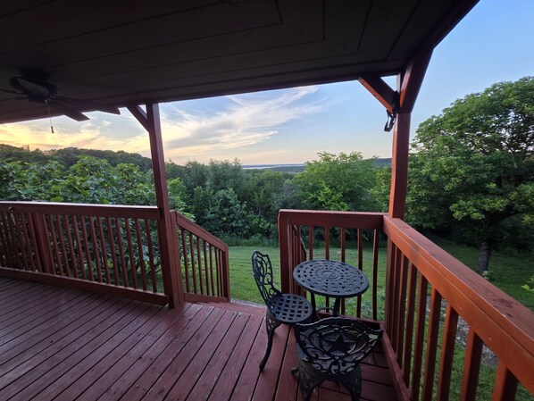 A wooden deck with a covered area, two metal tables, and chairs.