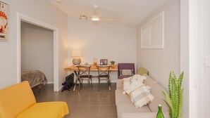 A compact living space with a dining area, a sofa, a bed, and a ceiling fan. - Cozy Cottage with Kitchen & Patio (East Tamworth)